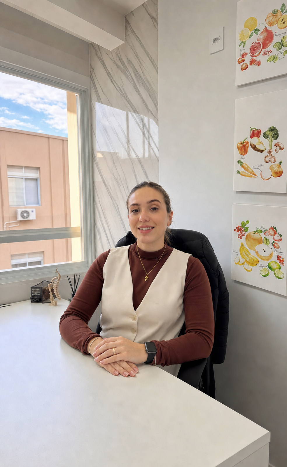 Kauani Truppel sorrindo, sentada em seu consultório em Florianópolis